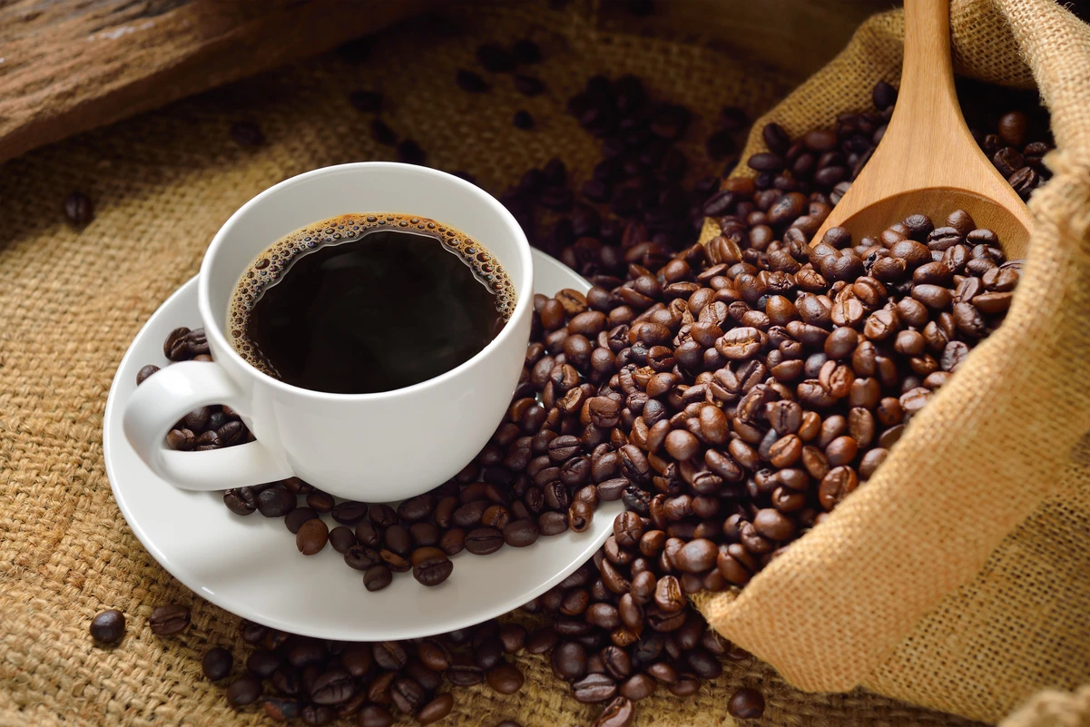 A freshly prepared cup of coffee with coffee beans